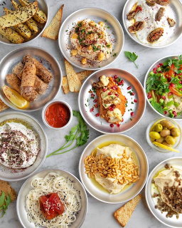 Overhead flatlay of brunch table with eggs, bread, salads, fruits, and breakfast dishes on white plates
