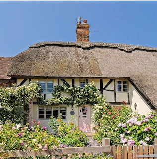 Traditional thatched cottage with timber beams and vibrant flower garden