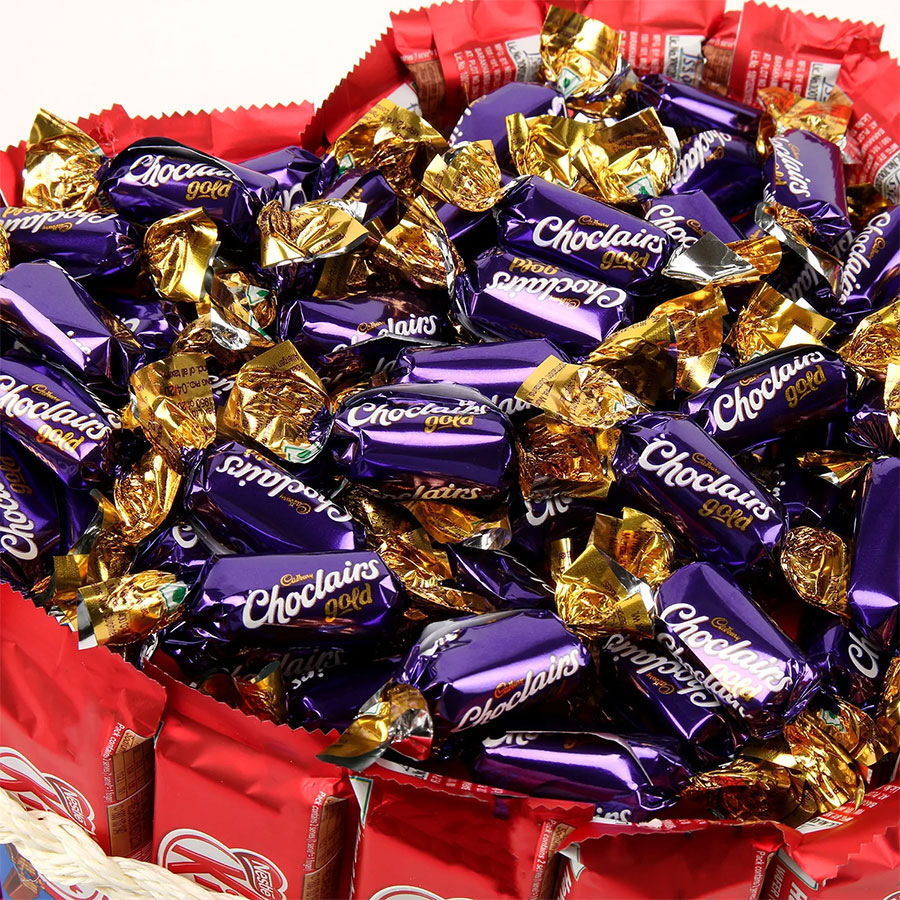 Close-up of purple and gold wrapped chocolate candies piled in a red container