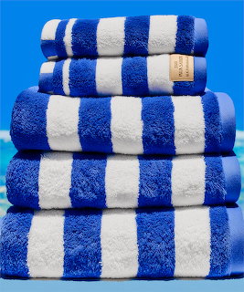 Stack of folded blue and white striped towels in different sizes on a blue background
