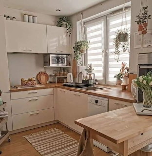 Bright modern kitchen with white cabinets, wood counters, window, and hanging plants