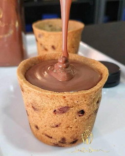 Cookie cup being filled with melted chocolate on a white surface