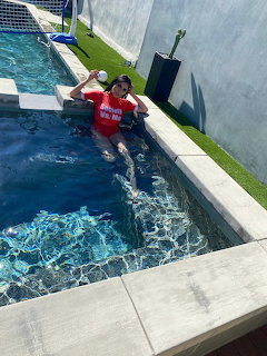 Woman in red swimsuit sitting by pool edge with turquoise water