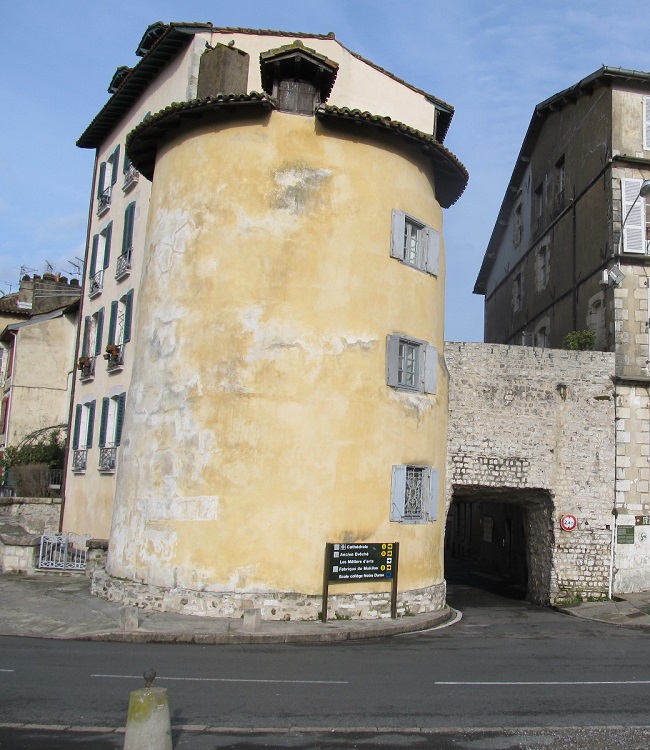 Old round yellow tower building beside a street in Bayonne
