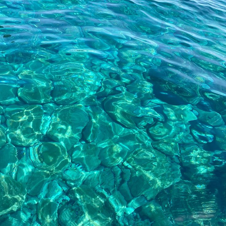 Clear turquoise sea water with ripples and rocks visible below the surface