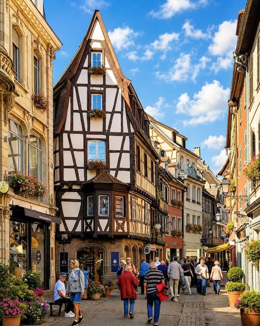 Cobblestone street in Colmar, France with colorful half-timbered buildings and pedestrians