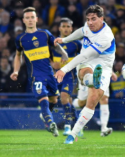 Soccer player in white and blue kicking the ball during a match