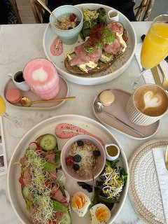 Overhead view of brunch table with toast, bagel, eggs, coffee and smoothie on white plates