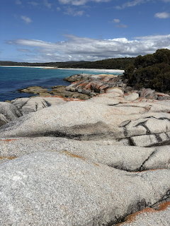 Large granite rocks on sandy beach with blue ocean and sky at Bay of Fires Tasmania