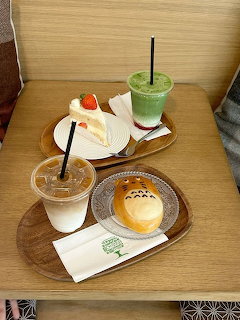 Wooden tray with Totoro character bread, iced drinks, and napkins on cafe table