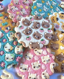 Assorted pastel-colored animal-shaped cookies with cute face decorations arranged on a white surface