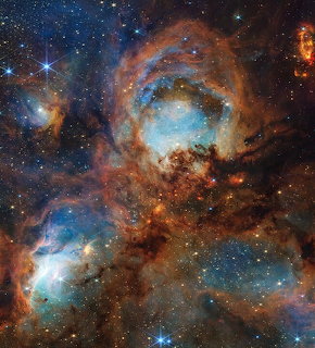 Cats Paw Nebula with swirling orange and blue gas clouds and scattered stars in deep space