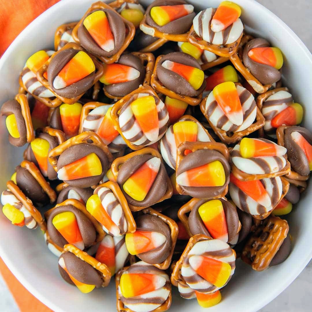 Close-up of a bowl filled with candy corn pretzel bites topped with chocolate and white drizzle