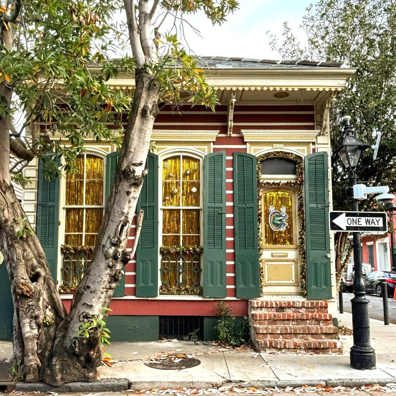 Small historic cottage decorated for Christmas with green shutters, red and white striped door trim, and holiday wreath