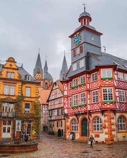 Half-timbered town hall with clock tower and colorful houses in a European square