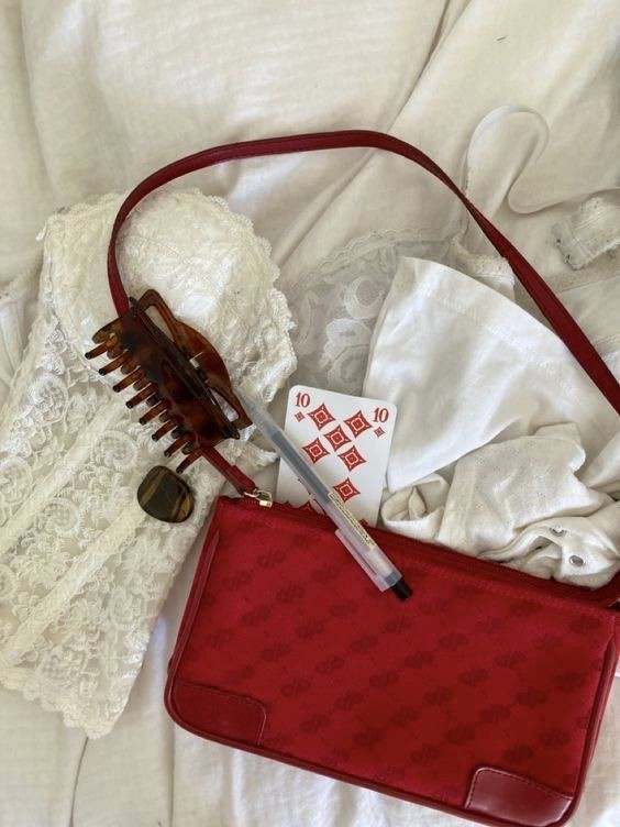 Red quilted handbag with lace fabric, hair claw clip, marker, and card on white background