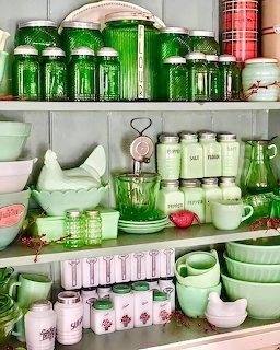 Shelves displaying a collection of vintage green jadeite kitchen items including canisters, bowls, and glassware