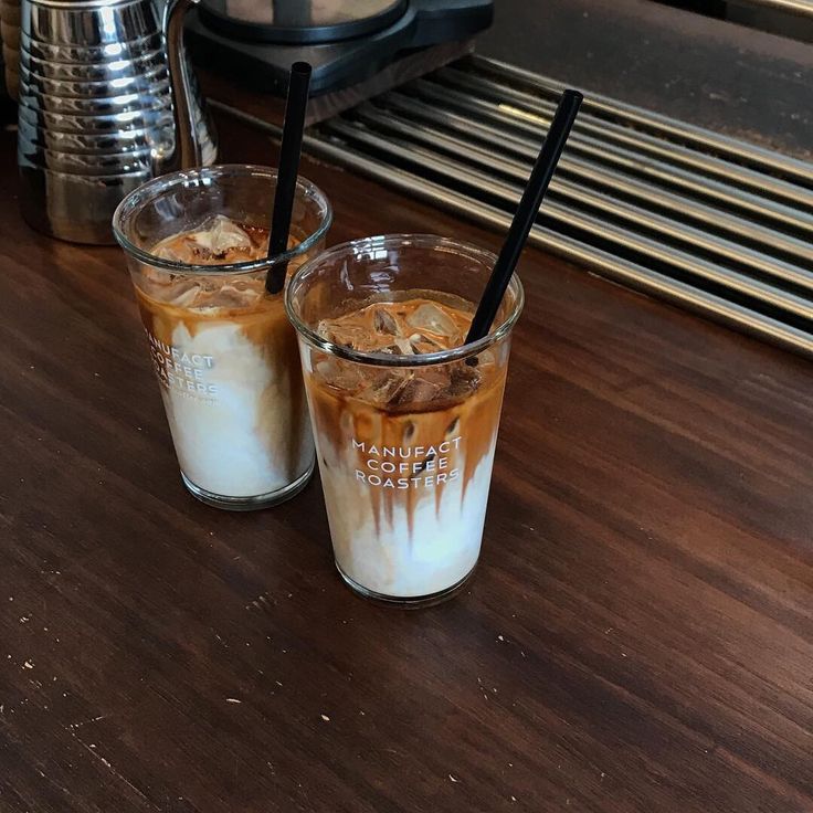 Two iced coffee drinks in clear glasses on a wooden counter