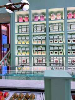 Mint green shelves in a pastel-themed cafe displaying organized rows of colorful pastries and desserts