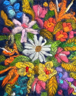 Colorful yarn flowers and leaves crafted from felted wool on a dark navy background