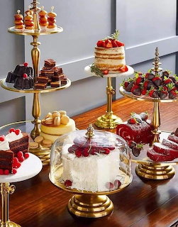 Assorted cakes and desserts arranged on gold tiered stands with fresh strawberries and berries