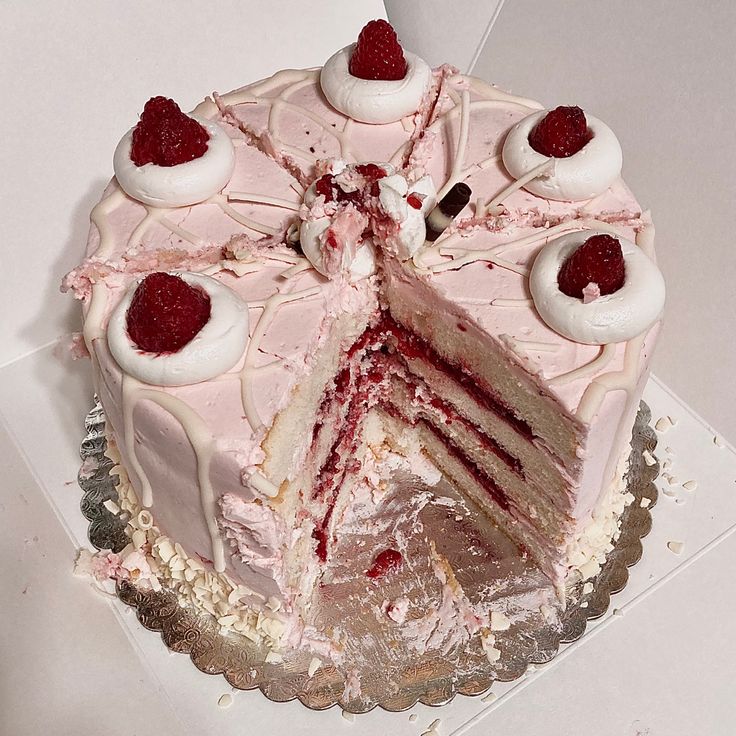 Pink frosted layer cake with raspberries and cream, slice cut revealing pink and white layers