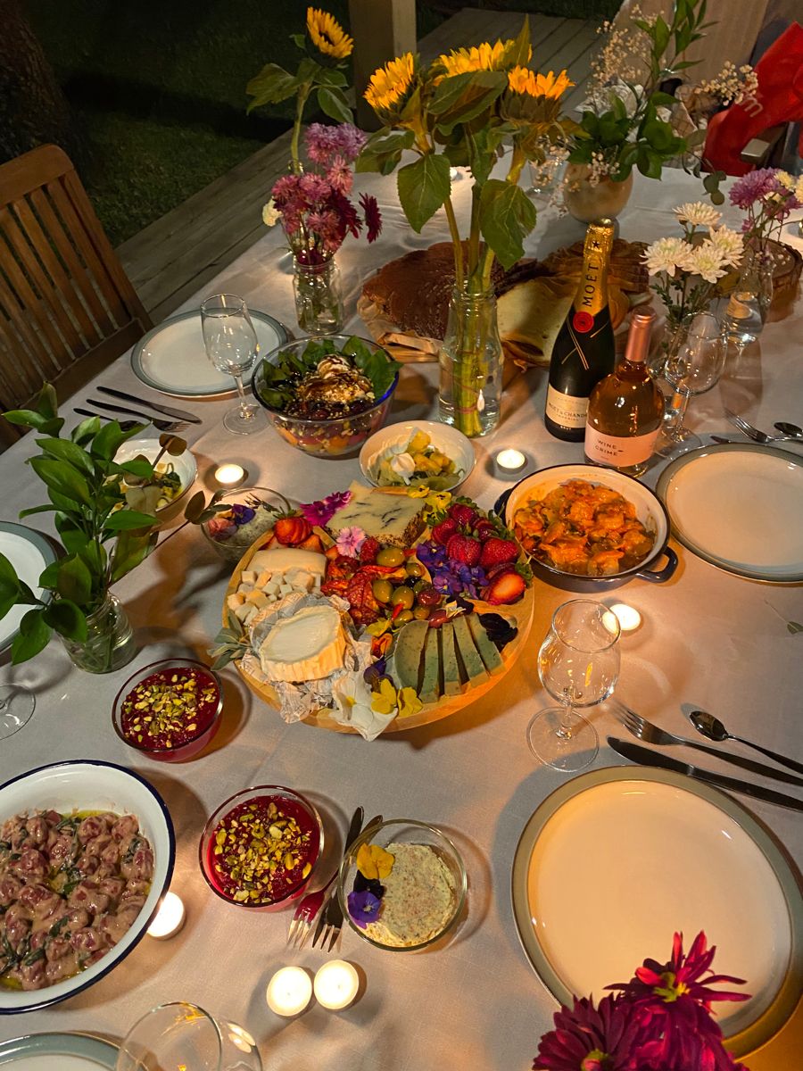 Overhead view of dinner table with multiple dishes, flower arrangements, candles, and place settings