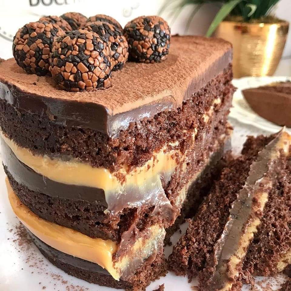 Close-up of a chocolate layer cake with ganache, cream filling, cocoa powder, and truffle toppings