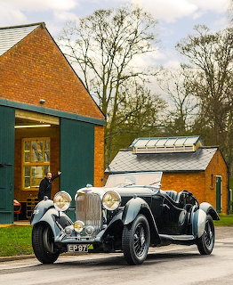 Black and silver 1937 Lagonda LG45 vintage car parked outside brick buildings