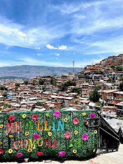 View over Medellin, Colombia with hillside houses, mountains, and a colorful flower sign in the foreground