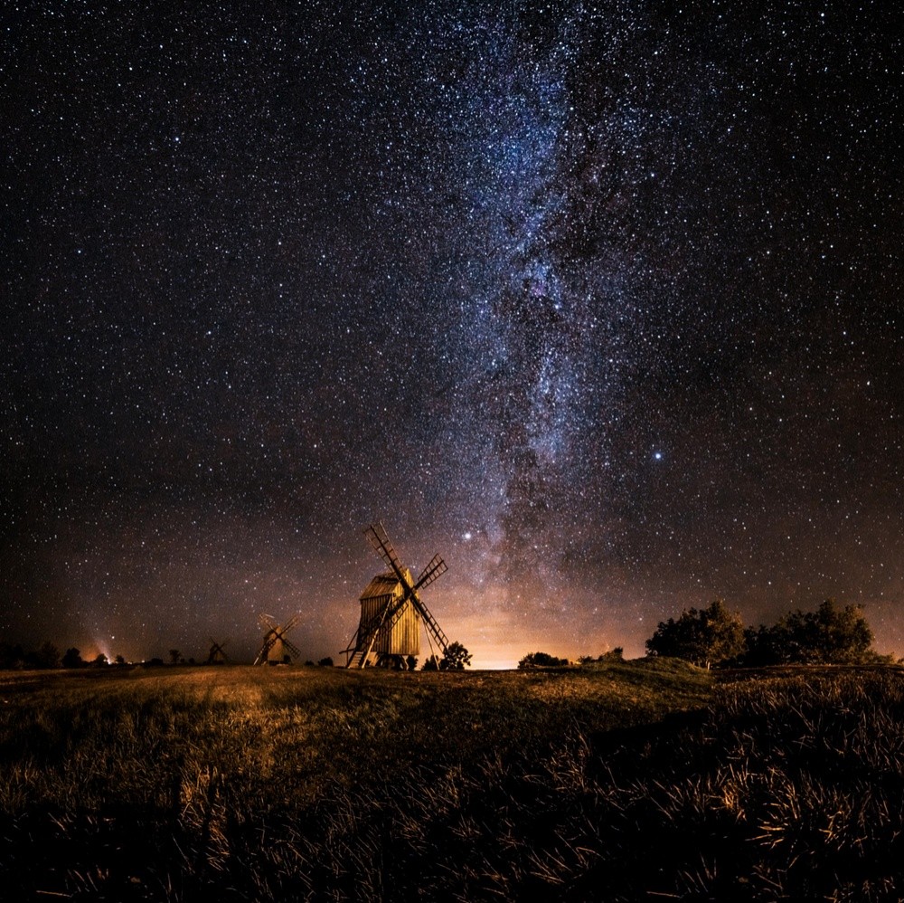 Milky Way over windmills in a dark field beneath a starry night sky