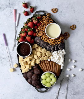 Overhead view of dessert board with chocolate fondue, fresh strawberries, pretzels, cookies, and marshmallows