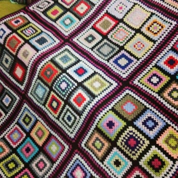 Colorful granny square crochet blanket with many multicolored squares in a patchwork arrangement