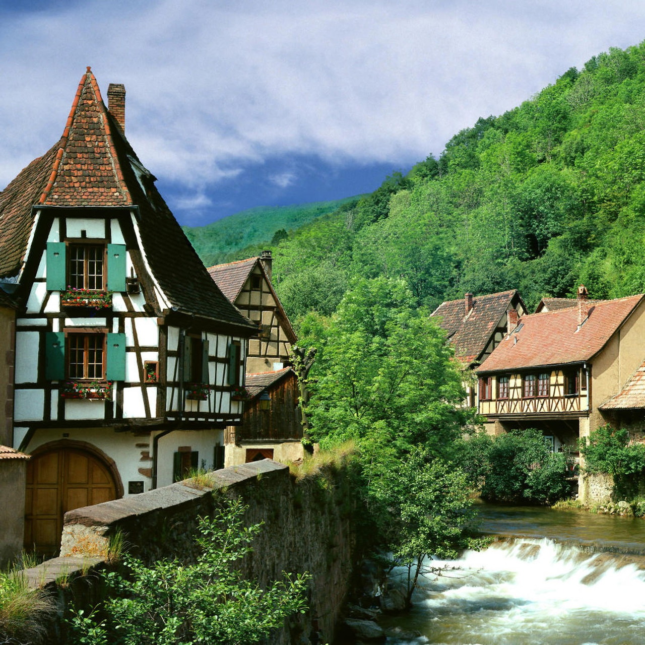 Half-timbered houses along a stream in a mountain valley