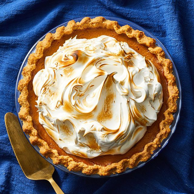 Overhead view of pumpkin pie topped with toasted meringue in a fluted crust on blue fabric