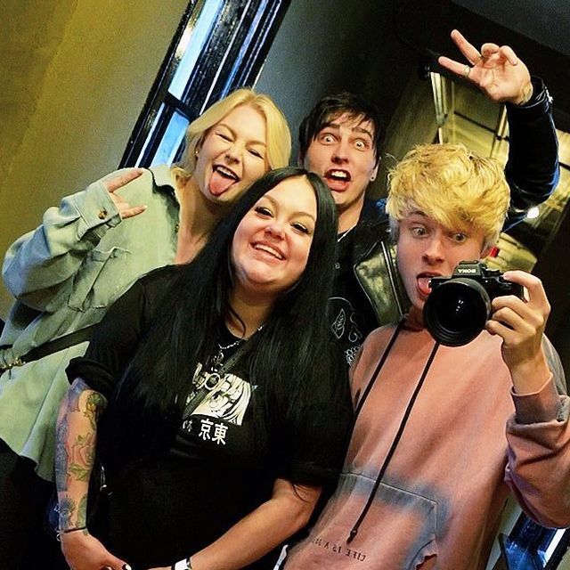 Four friends posing for a playful indoor mirror selfie with a camera