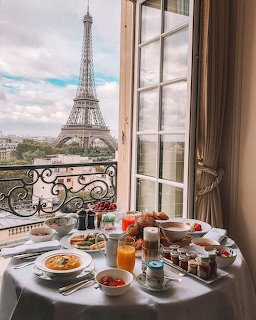 Breakfast table on balcony overlooking Eiffel Tower in Paris with pastries and coffee