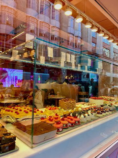 Bakery cafe window with cakes, pastries, and colorful desserts behind glass