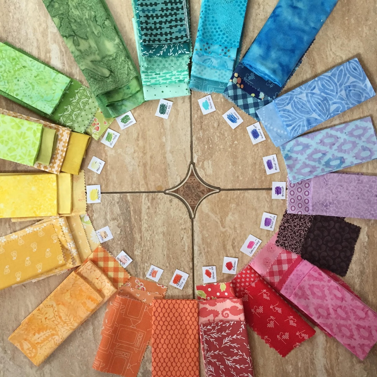 Colorful fabric samples arranged in a rainbow circle on wood surface