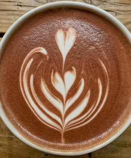 Overhead view of a cappuccino cup with tulip latte art on a wooden table