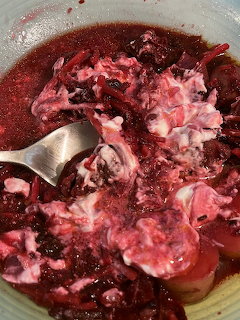 Bowl of dark red borscht soup with beef chunks and sour cream swirled on top