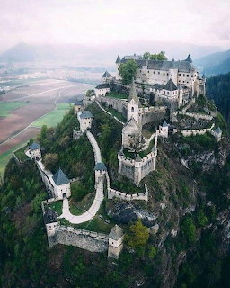 Aerial view of a stone castle fortress on a rocky hill with towers and surrounding countryside