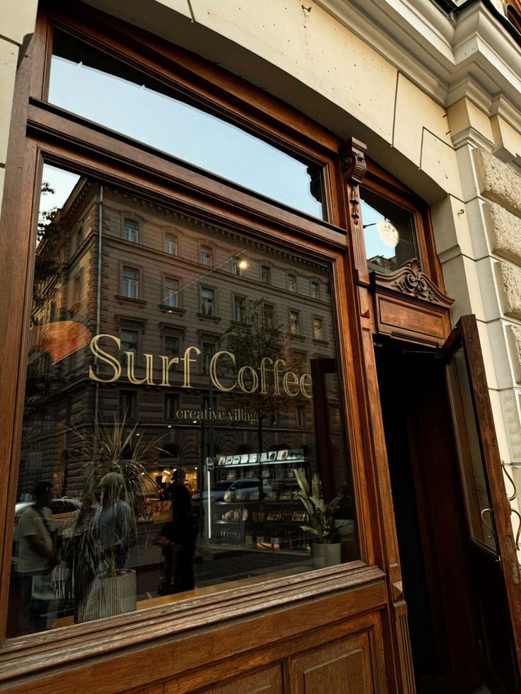 Wooden-framed glass storefront of Surf Coffee café with reflections of street architecture