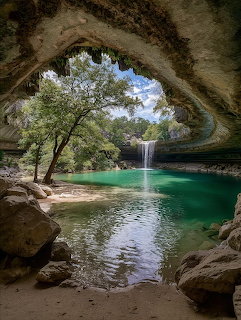 Rocky grotto opening framing Hamilton Pool with a waterfall, turquoise water, and trees in Texas