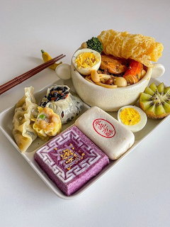 Korean meal platter with rice cakes, dumplings, eggs, and colorful side dishes on white tray