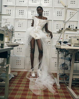 Model wearing white bridal corset dress with tulle train in a fashion design studio