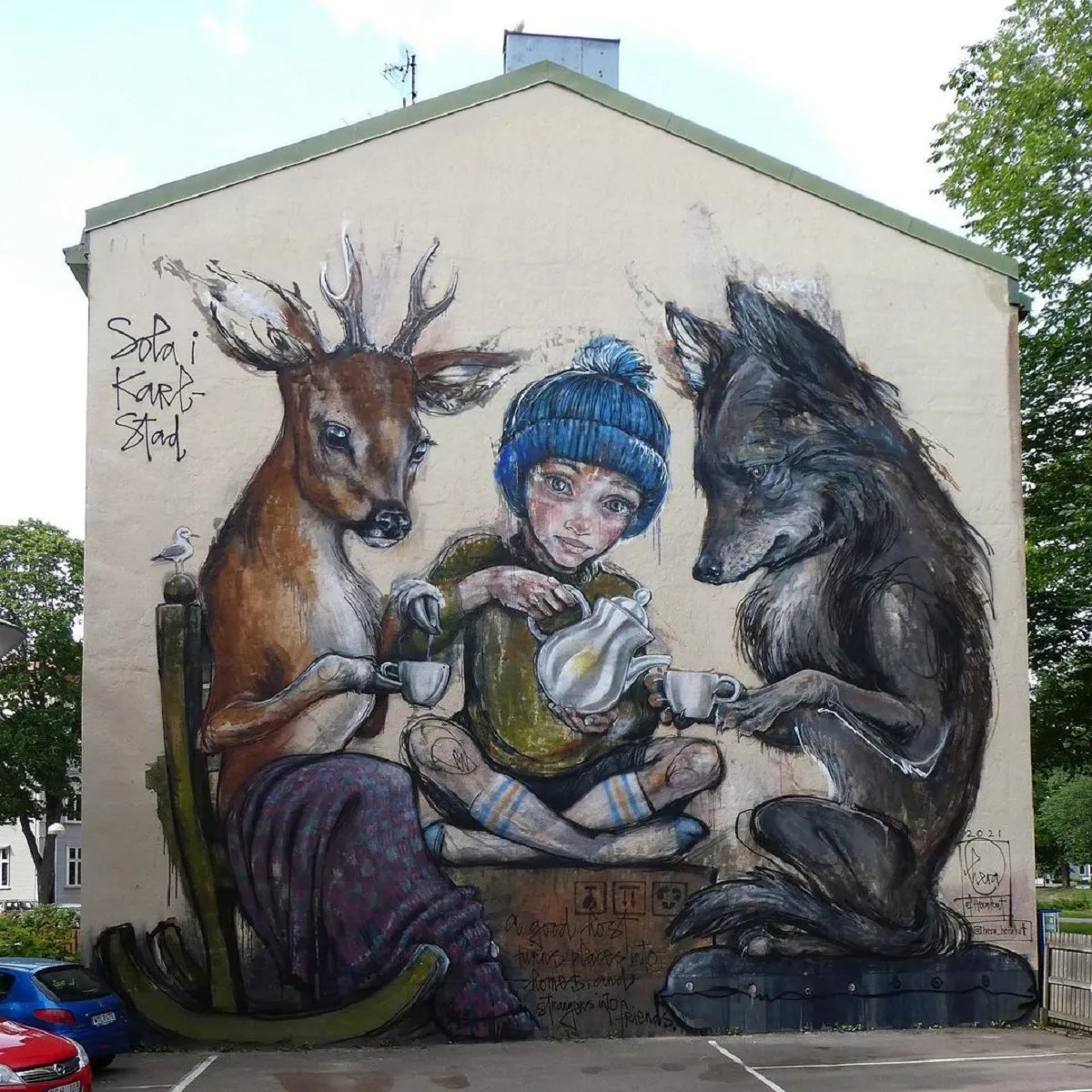 Street art mural showing child with blue beanie between deer and wolf on building wall