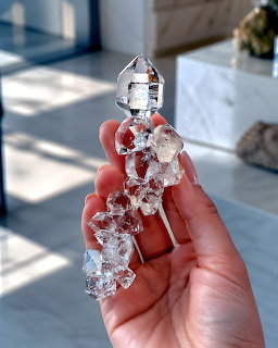 Hand holding a clear quartz crystal cluster with multiple points in natural light
