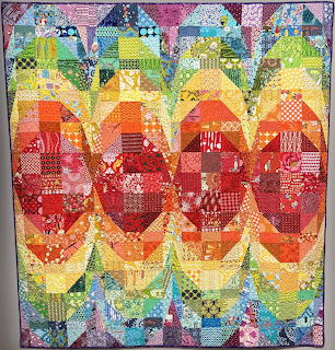 Handmade quilt with rainbow chevron zigzag pattern made from assorted patchwork fabric pieces