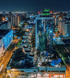 Aerial nightime view of Puerto Ordaz city with illuminated hotel building and blue-lit swimming pool